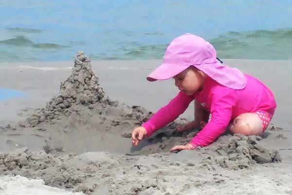 kid on the beach wearing sun protective clothing